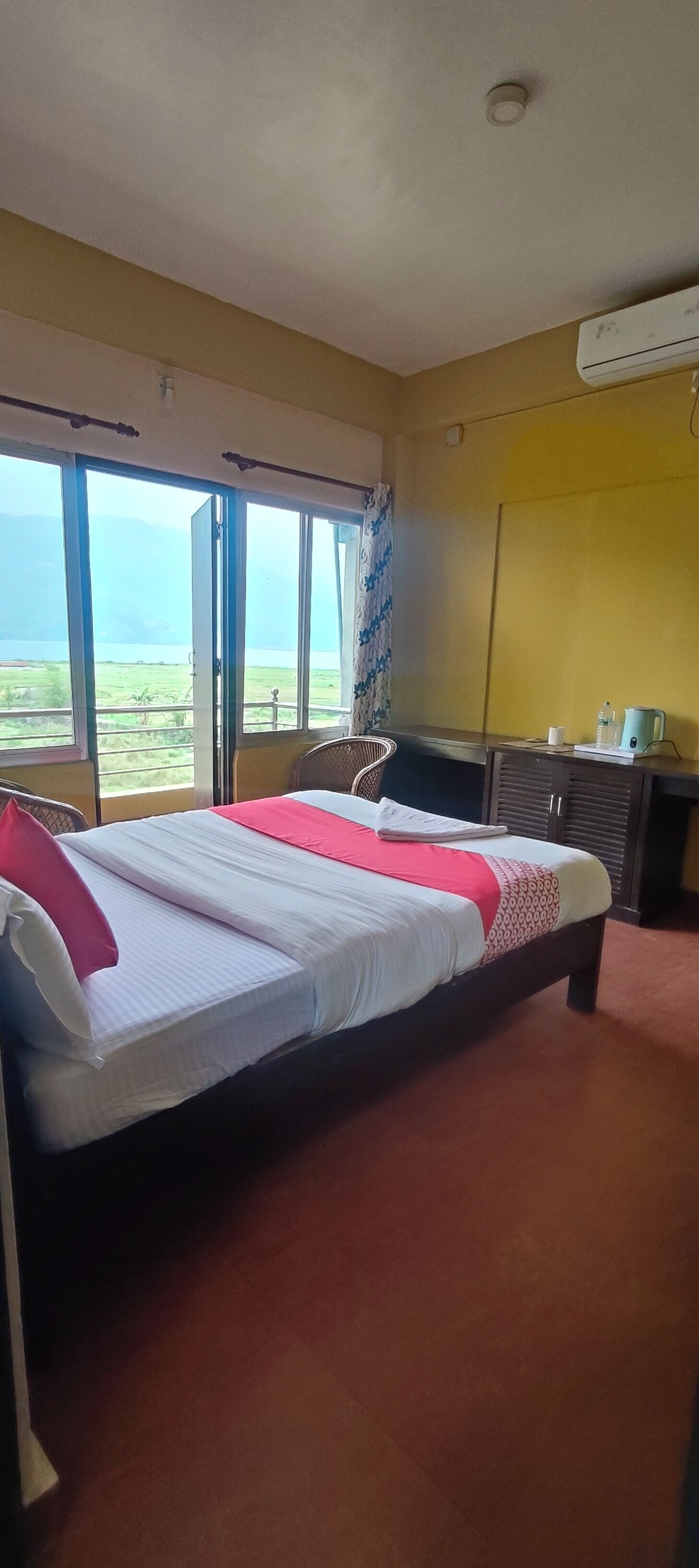 Una camera d'albergo con un letto, una scrivania, un condizionatore d'aria e vista sull'esterno.