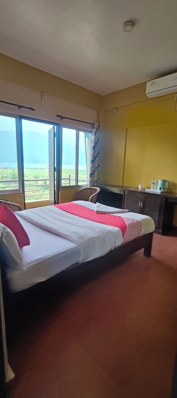 A hotel room with a bed, a desk, an air conditioner, and a view of the outdoors. - Hotel August International (Pokhara)