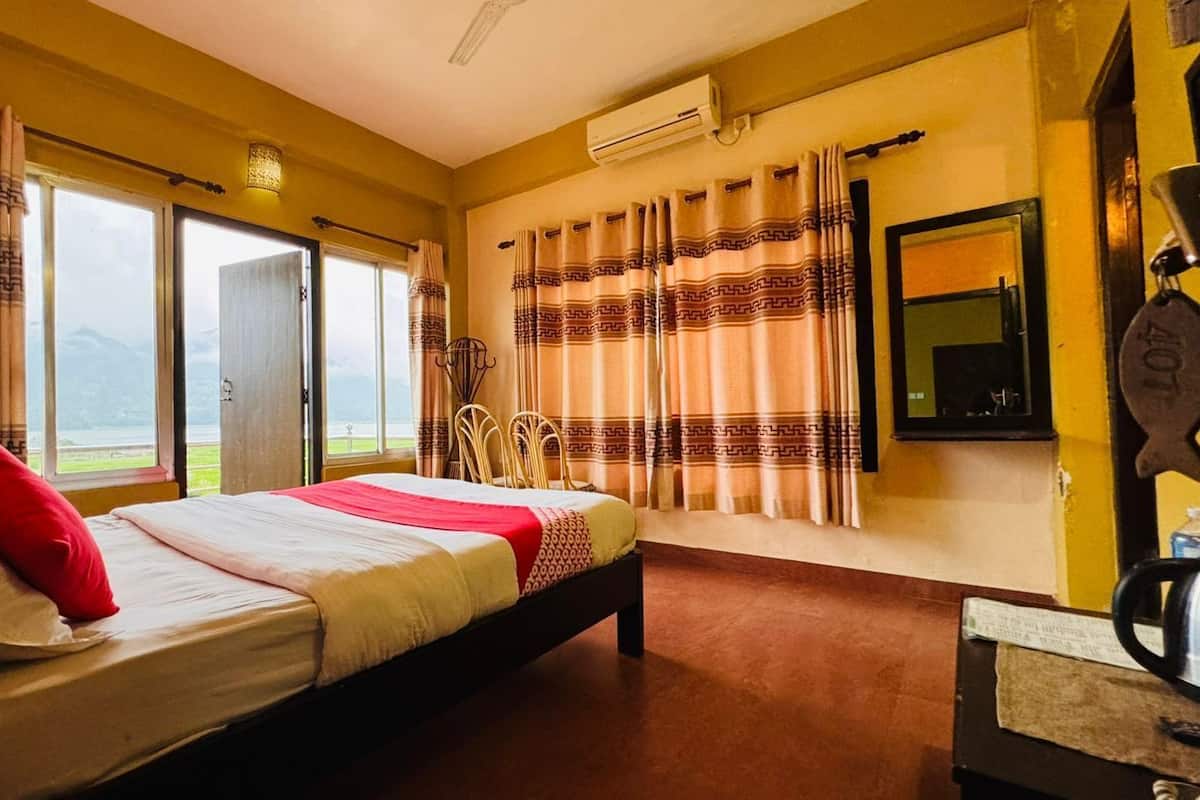 A hotel room with a bed, a desk, and a view of the outdoors.