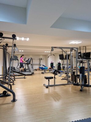 A gym with treadmills, weight machines, and a bench press.