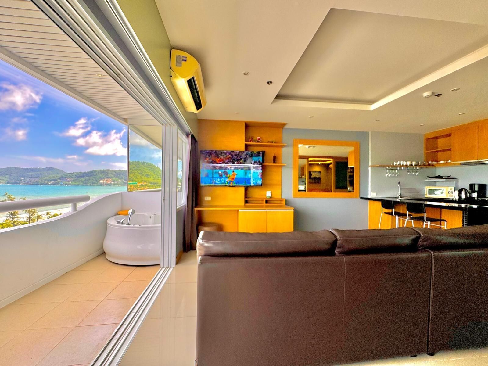 Una sala de estar moderna con un sofá, un televisor y una zona de cocina con una mesa de comedor.