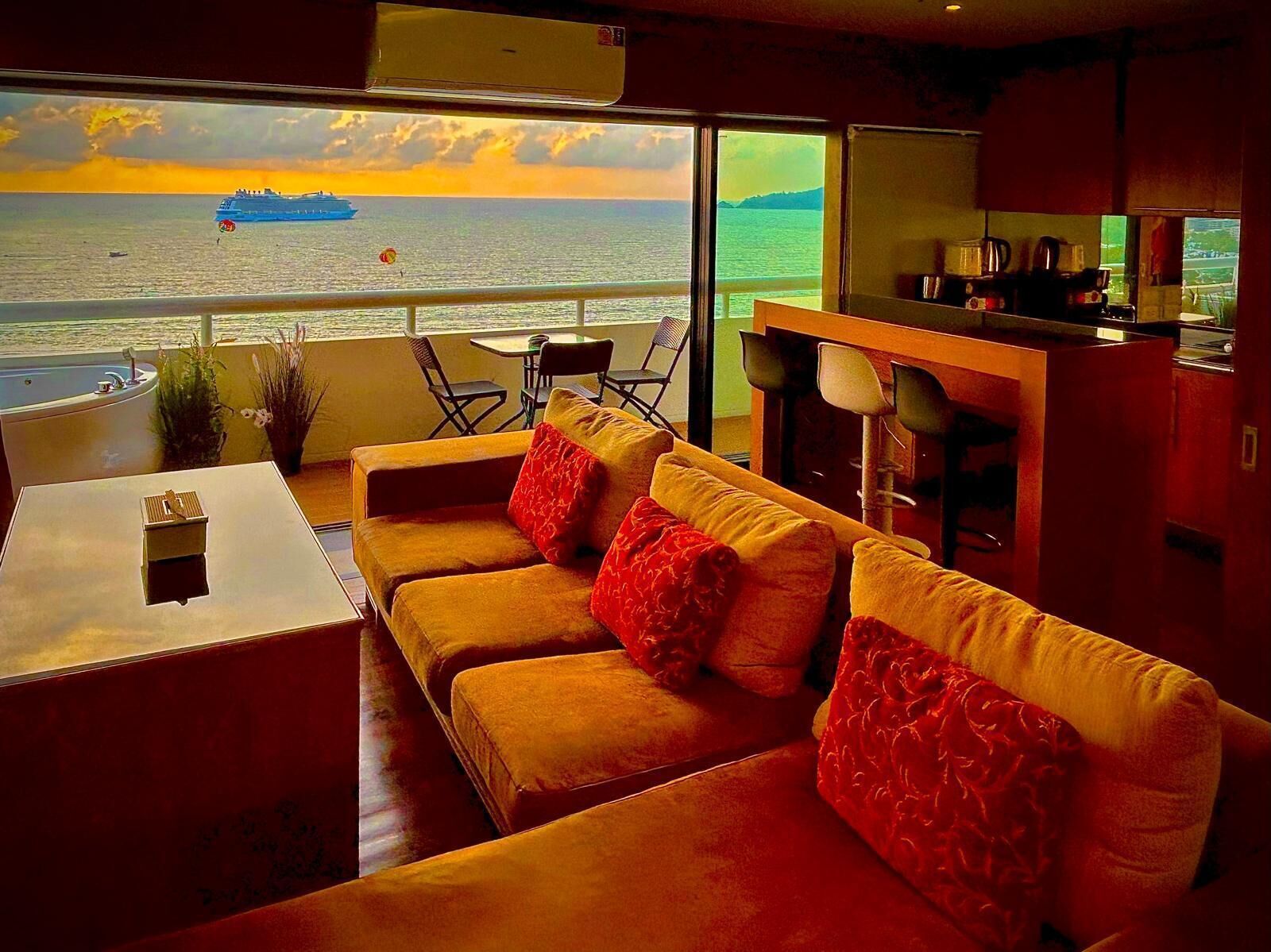 Un intérieur moderne avec un ensemble de canapés, une petite table et une vue sur l’océan et un navire.