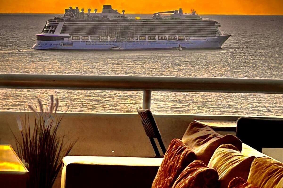 Ein Kreuzfahrtschiff auf dem Ozean, im Hintergrund ein Sonnenuntergang.