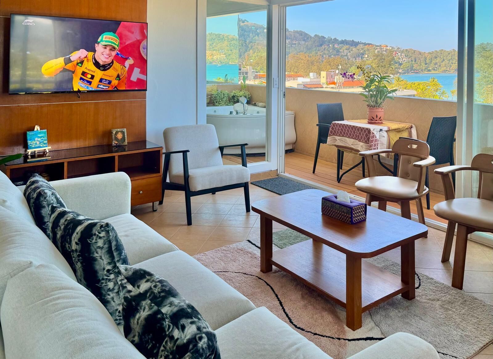 Una sala de estar moderna con un sofá, sillones, una mesa de centro y un televisor montado en la pared.