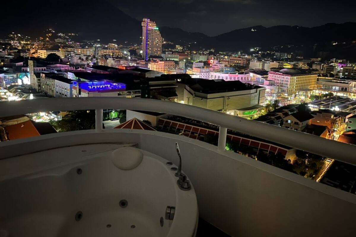 Ein Balkon mit Whirlpool mit Blick auf eine nächtliche Stadtlandschaft.