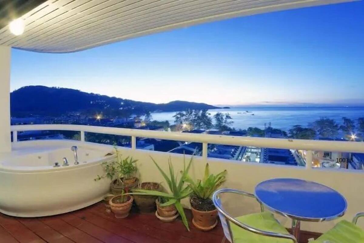 Ein Balkon mit Whirlpool, Topfpflanzen und Blick auf das Meer und die Hügel.