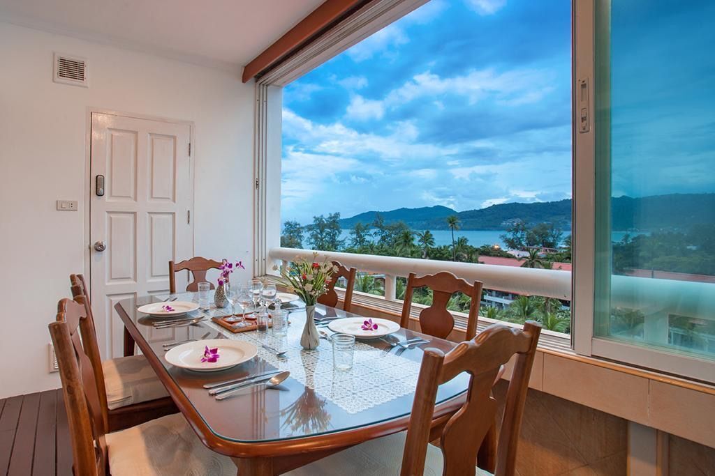 Zona pranzo con tavolo imbandito per quattro, vista mare e montagne, e un'ampia finestra.