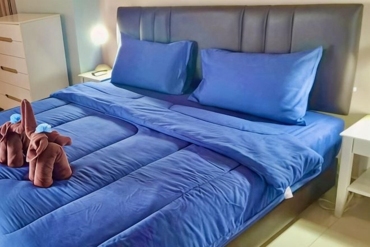 A bed with blue bedding, a headboard, and a nightstand with a lamp.