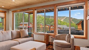 A modern interior with large windows offering a view of a mountainous landscape. - Schweitzer Lux Powder Dreams I Hot Tub I Families (Sandpoint)