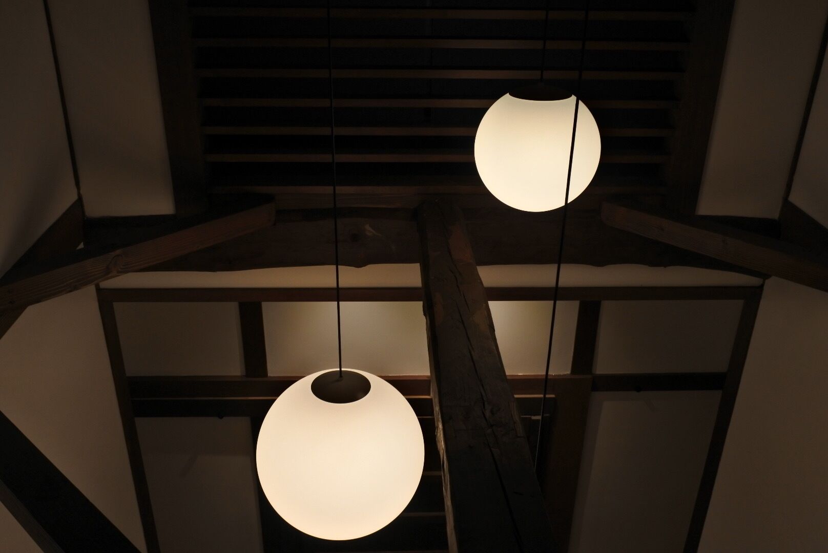 Interior moderno com vigas de madeira e luminárias pendentes esféricas.
