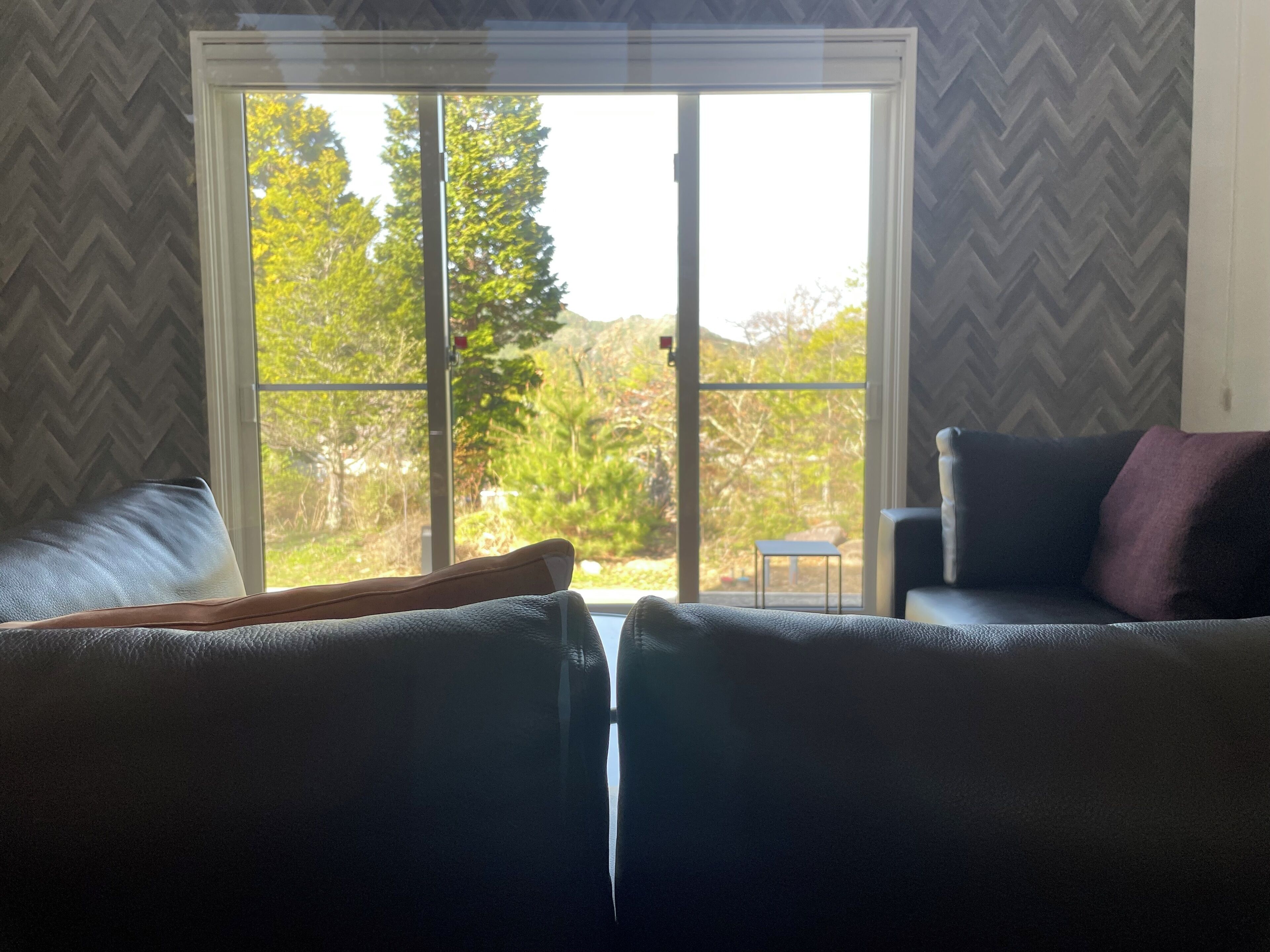 Una habitación con dos sofás orientados hacia un amplio ventanal corredera que da a un jardín.