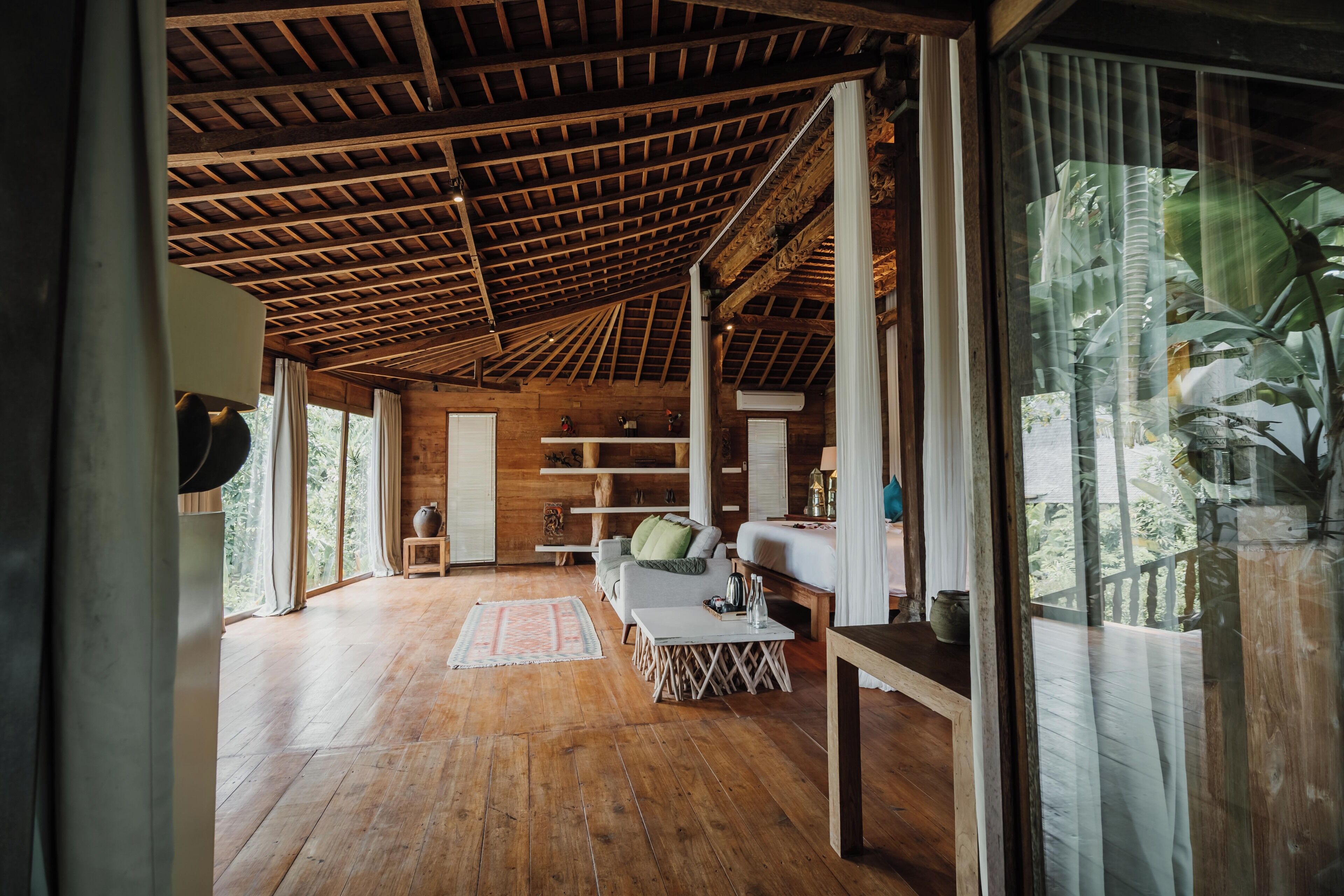 A spacious room with a wooden ceiling, large windows, and a cozy seating area with a sofa and a coffee table.