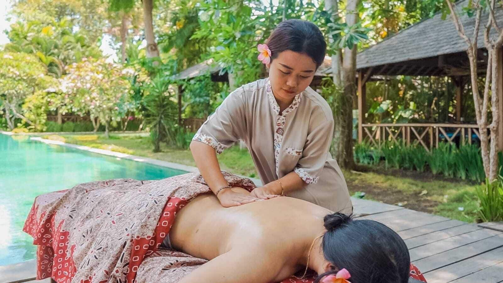 A person receiving a massage by a poolside.