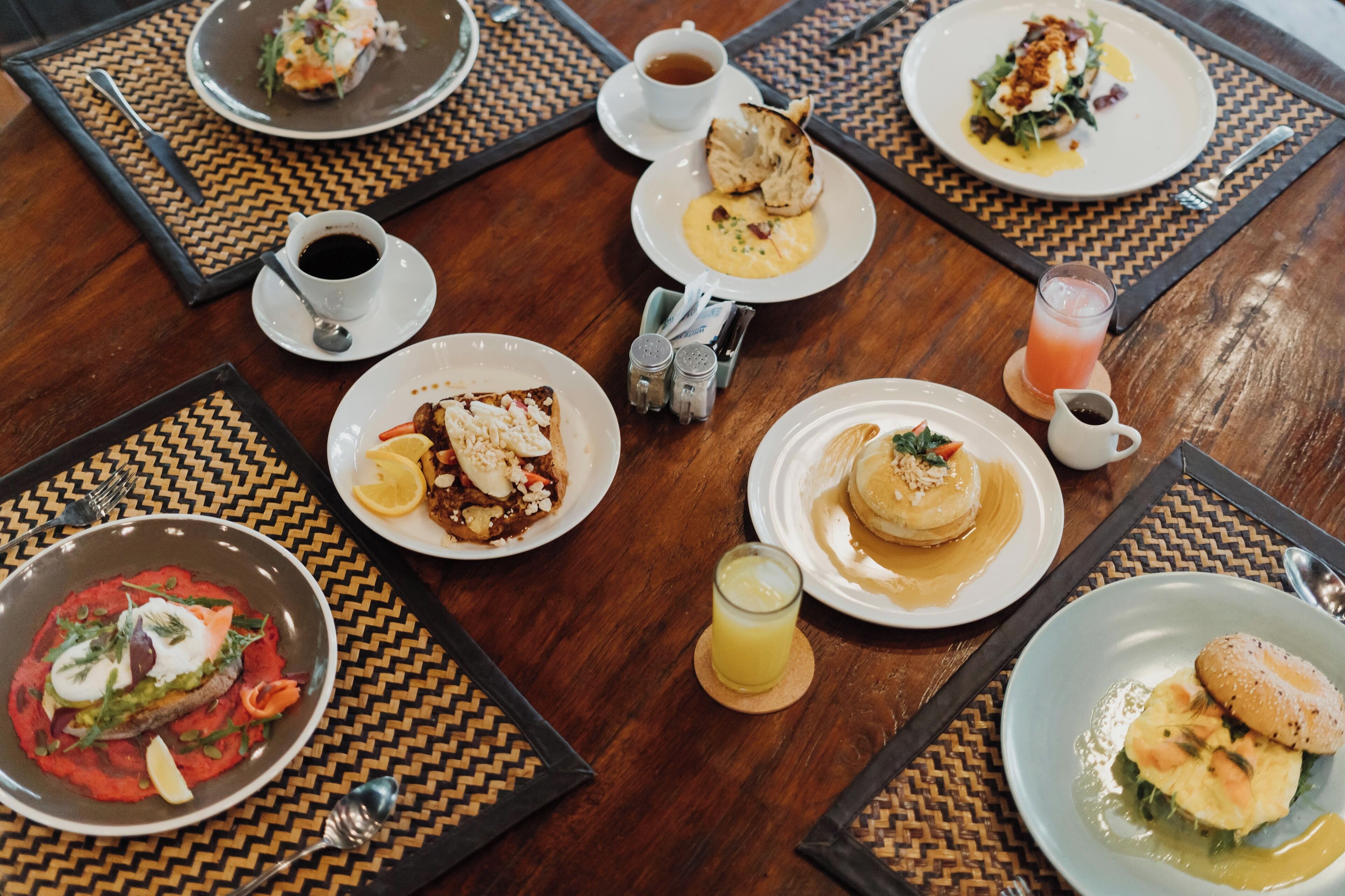 A dining table with various dishes and beverages, including plates of food, a cup of coffee, and a glass of juice.