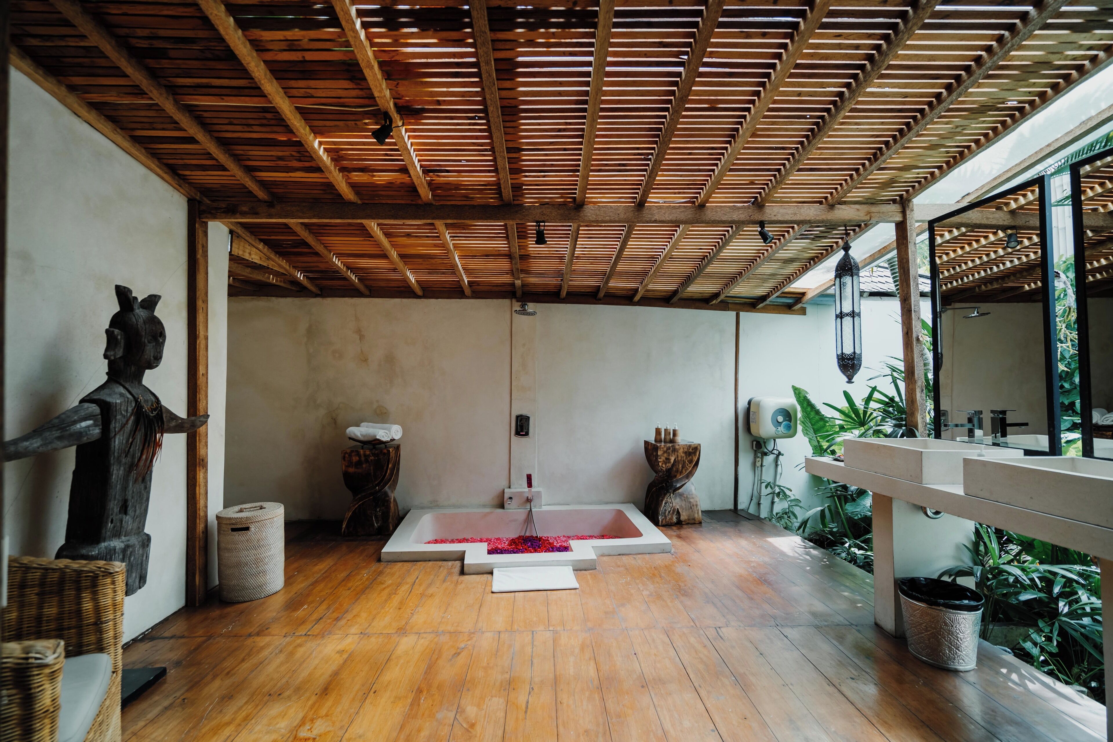 Un área de spa con techo de madera, una bañera grande y un espejo.