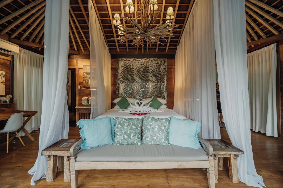 A bedroom with a wooden ceiling, a canopy bed, and a chandelier.
