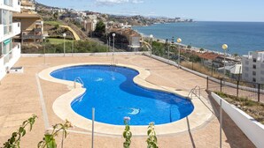 A swimming pool with a wavy design, surrounded by a paved area and a fence. - Sunstay Diamond Loft Fuengirola Beach (Fuengirola)