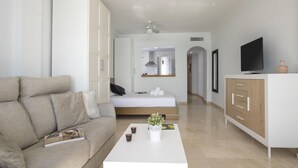A modern living room with a sofa, a coffee table, a bed, a TV, and a kitchenette. - Sunstay Diamond Loft Fuengirola Beach (Fuengirola)