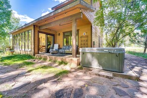 A wooden cabin with a covered porch, stone pathway, and a hot tub. - Durango Snow Days: Hot Tub & Fire Pit (Durango)