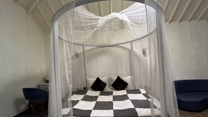 Una cama redonda con una colcha a cuadros, un dosel y dos almohadas.