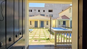 Vista desde el interior de un edificio a un patio exterior con piscina, suelo de baldosas y un tapete azul.