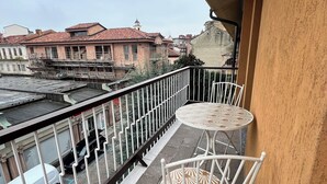 A balcony with a view of buildings and a river. There are two white metal chairs and a small round table. - Aster apartment - Free Parking in the historic center of Alba - Langhe (Alba)