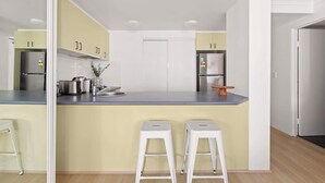 A modern kitchen with a central island, two bar stools, and stainless steel appliances.