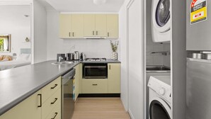 A compact kitchen with a washing machine, a stove, and a sink.