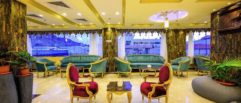 A lobby with green sofas, red chairs, and a marble floor.