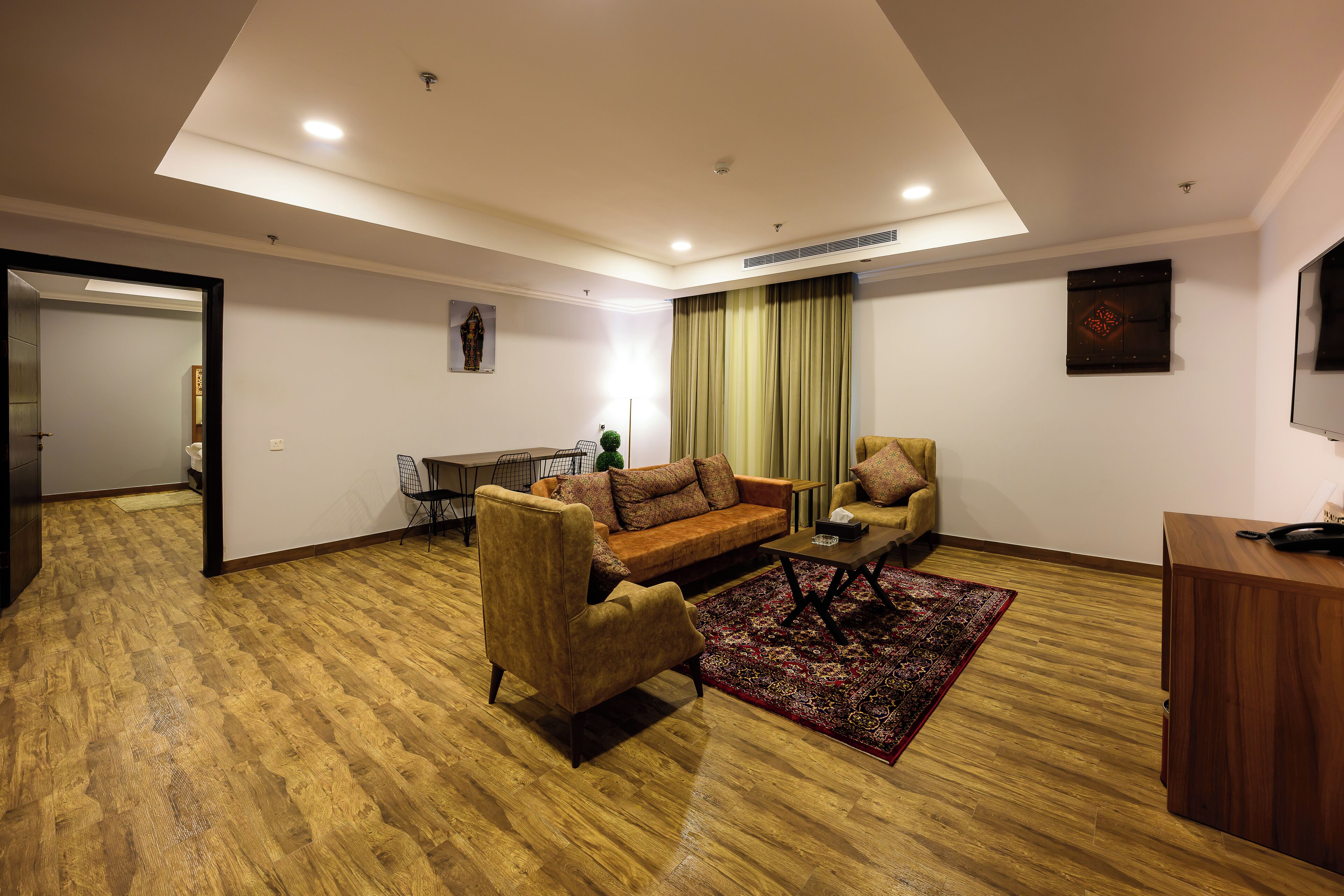 Una sala de estar moderna con sofá, sillones, una mesa de centro y televisor.