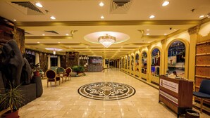 A hotel lobby with a chandelier, a reception desk, and a decorative floor pattern. - Zaman Homeland Hotel (Taif)