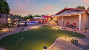 A backyard with a putting green, a pool, and outdoor seating. - The Rusty Cactus | Heated Salt Pool, Spa, & More! (Phoenix)