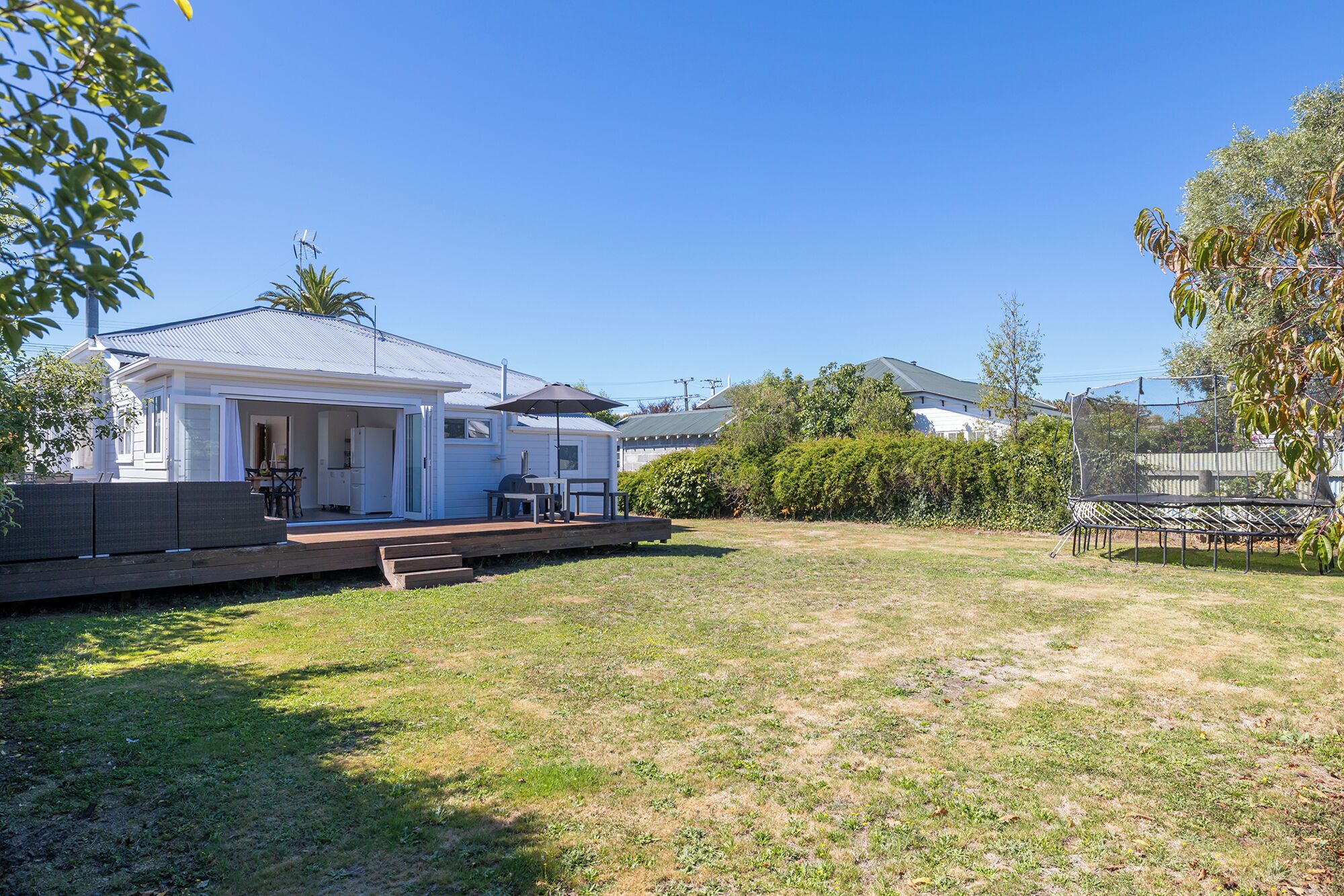 A residential property with a covered patio, outdoor furniture, and a trampoline.