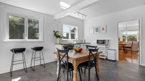 Una cocina moderna con una mesa de madera, sillas negras y un frutero.