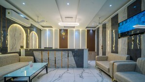 Una hall moderna con pavimento in marmo, una reception, divani e un televisore a schermo piatto.