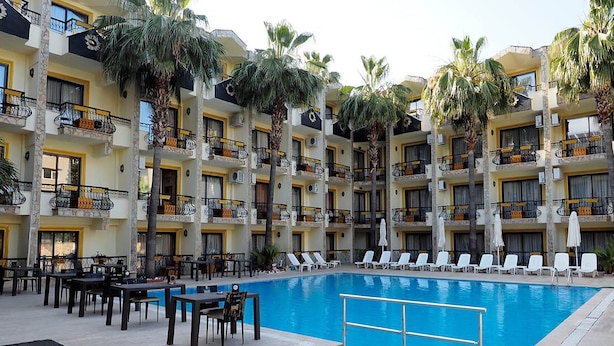 Un espace piscine d’hôtel doté de plusieurs balcons, de chaises longues et de tables.