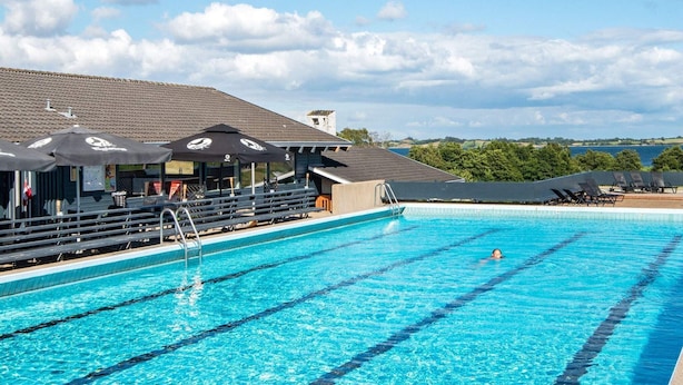 A swimming pool with clear blue water, lounge chairs, and umbrellas. - 5 Person Holiday Home in Aabenraa (Aabenraa)