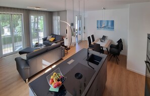 A modern living area with a sofa, dining table, and kitchen island. - Apartment 'Strandblick' with Sea View, Balcony and Wi-Fi (Binz)