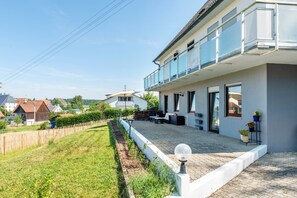 A residential property with a paved patio, a white fence, and a balcony with railings. - Apartment 'Fribo' with Private Terrace and Wi-Fi (Ostrach)