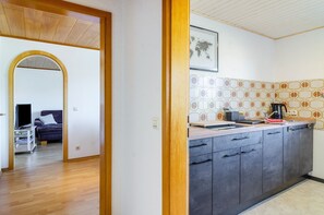 Una cocina moderna con gabinetes grises, un salpicadero de azulejos y un techo de madera.