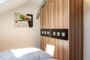 Un dormitorio con una cama, un armario de madera y una obra de arte colgada en la pared.