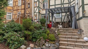 Ein traditionelles Fachwerkhäuschen mit Garten, Treppen und einer überdachten Außenveranda.