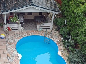 Una piscina con cubierta de madera y un área de descanso techada.