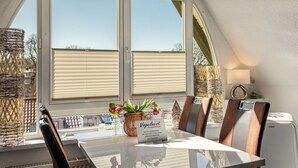 Ein Essbereich mit Tisch, Stühlen, einem Schild und Blick durch ein Fenster.