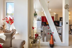 Una sala de estar moderna con un sofá, una mesa de centro de vidrio y un jarrón con flores rojas.