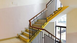 Eine Treppe mit gelben Stufen und schwarzen Geländern, die zu einer oberen Etage führt.