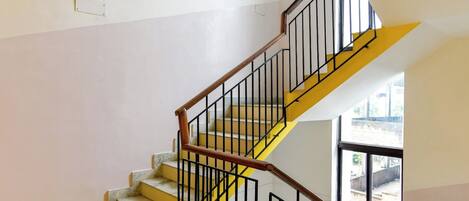 A staircase with yellow steps and black railings, leading to an upper floor.