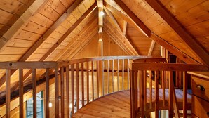 Un interior de madera con una escalera curva y un techo alto.