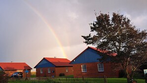 Una hilera de casas con tejados rojos y un arcoíris en el cielo.