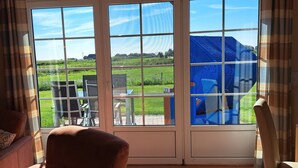 A room with a large sliding glass door leading to an outdoor area with a table and chairs. - Holiday Home 'Ferienhaus Heverstrom' with Shared Garden and Wi-Fi (Pellworm)